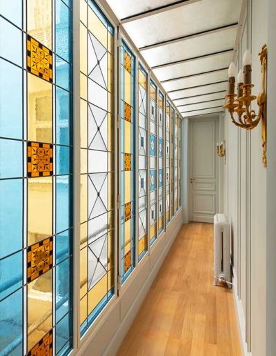 Couloir avec baie en vitraux colorés jaune et bleu